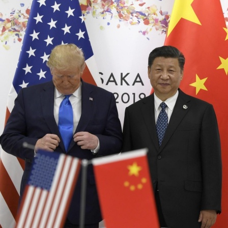 Donald Trump richtet seinen Anzug, während er auf dem G20-Gipfel mit Xi Jinping für ein Foto posiert.