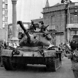 Türkischer Panzer fährt durch zyprische Stadt, am Rand stehen applaudierende Menschen