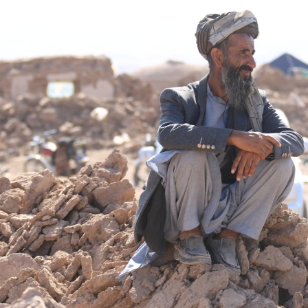 Ein Mann sitzt auf den Trümmern von Häusern in einem vom Erdbeben betroffenen Dorf in der Region Zinda.
      