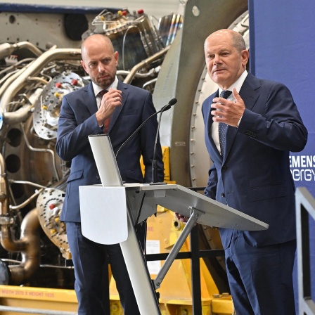 Bundeskanzler Olaf Scholz (SPD) steht mit Christian Bruch (l), Vorstandsvorsitzender von Siemens Energy, an der in Kanada für die Erdgas-Pipeline Nordstream 1 gewarteten Turbine.