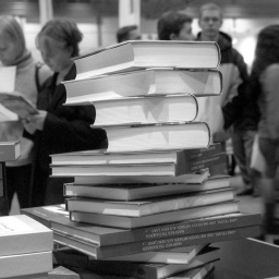 Ein Bücherstapel und Besucher*Innen auf der Leipziger Buchmesse
