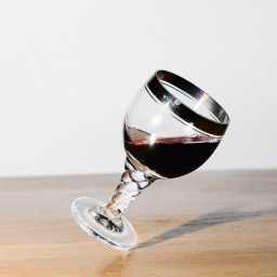Ein mit Rowein gefülltes Weinglas balanciert schräg auf dem Fuß stehend