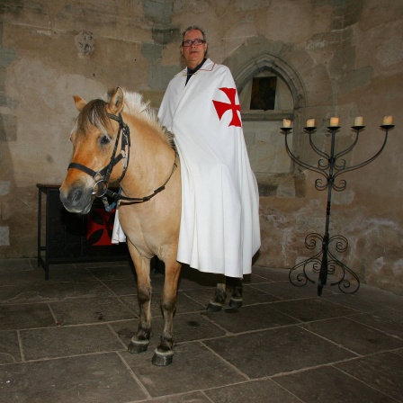 Achim Lipp (Verein - Freunde des Templerhofes e.V.-) im Gewand eines Templers auf einem Pferd in der Templerkapelle in Mücheln