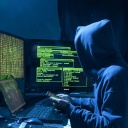 Ein Hacker sitzt vor verschiedenen Rechnern.
