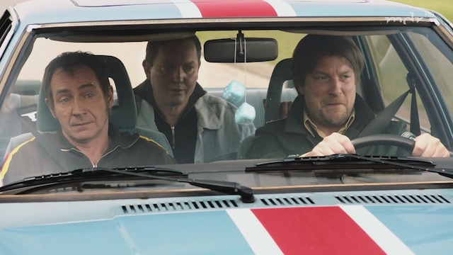 Drei Männer sitzen in einem Auto.