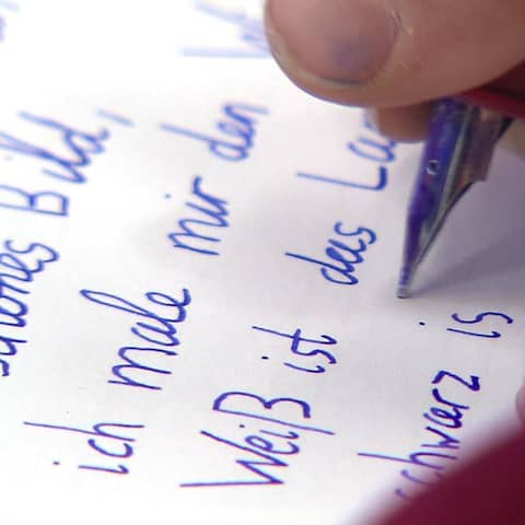 Ein Kind schreibt mit einem Füller auf ein Stück Papier