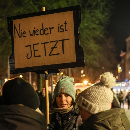 Bei einer Demo in Köln trägt eine Frau ein Schild mit der Aufschrift &#034;Nie wieder ist jetzt&#034;.