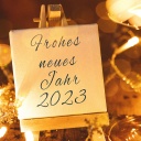 Tafel neben einem Sektglas mit dem Neujahr Gruß "Frohes Neues Jahr 2023"