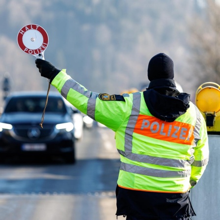 Ein Polizist der Bayerischen Grenzpolizei stoppt am 6. Februar 2025 am Grenzübergang von Österreich nach Deutschland in Oberaudorf (Bayern) ein Auto an einer Kontrollstelle der Polizei. 