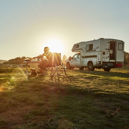 Ein Camper mit Wohnmobil bei Sonnenuntergang.