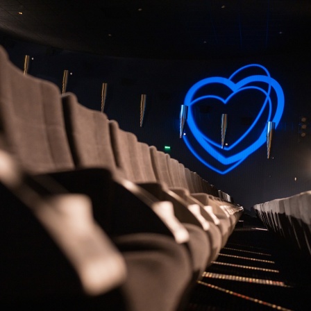 Blaue Herzen, Symbol des Filmfestivals Max Opühls Preis, sind an die Wand eines leeren Kinosaal projiziert.