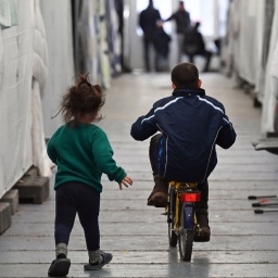 Geflüchtete Kinder sind in einer improvisierten Flüchtlingsunterkunft unterwegs.