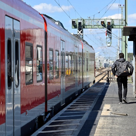 Ein Mann geht ein Gleis entlang, an dem eine S-Bahn der Deutschen Bahn steht