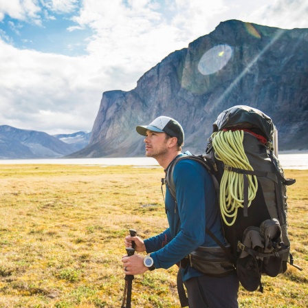 Backpacker mit schwerem Rucksack vor Bergpanorama in Kanada: Wenn man die Schultern zu stark belastet, reagiert die Muskulatur darauf - in der Regel mit Verspannungen, aber auch mit Druckschmerzen. Die entstehen durch die Belastung der Träger; die rufen Druckstellen hervor.