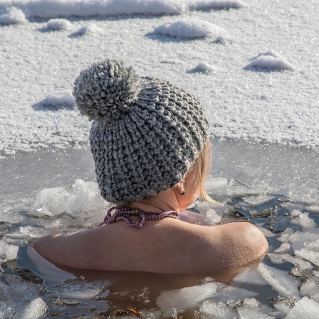 Eine junge Frau in einem Wasserloch beim Eisbaden