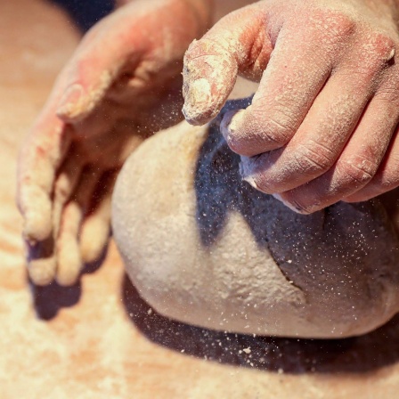Ein Bäcker formt mit seinen Händen ein Brot