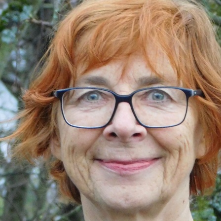 Eine Frau mit rötlichen Haaren schaut grinsend nach vorne.