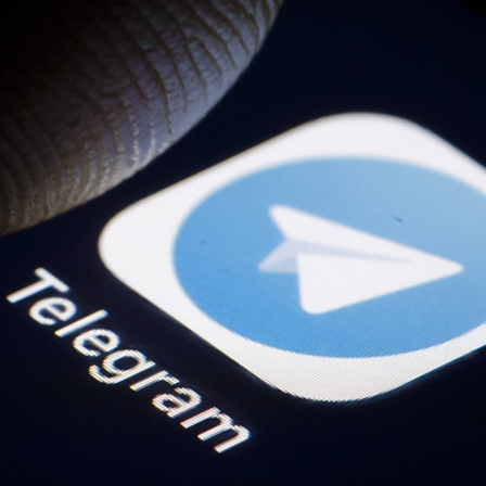 Die App des Messengers Telegram auf einem Smartphone, darüber ein Finger