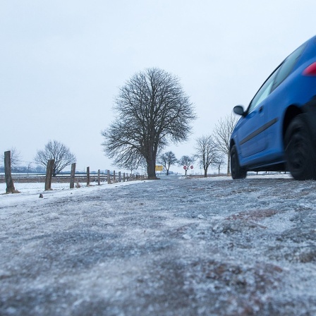 Ein Auto fährt über eine vereiste Straße.