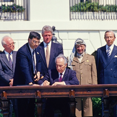 Israels Außenminister Shimon Peres (li.) unterzeichnet das historische Oslo-Abkommen (1993). Rechts von ihm Palästinenser-Präsident Jassir Arafat, links von ihm US-Präsident Bill Clinton.