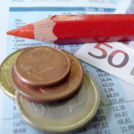 ein Rotstift liegt auf einem Zettel mit Dax-Werten und Geld