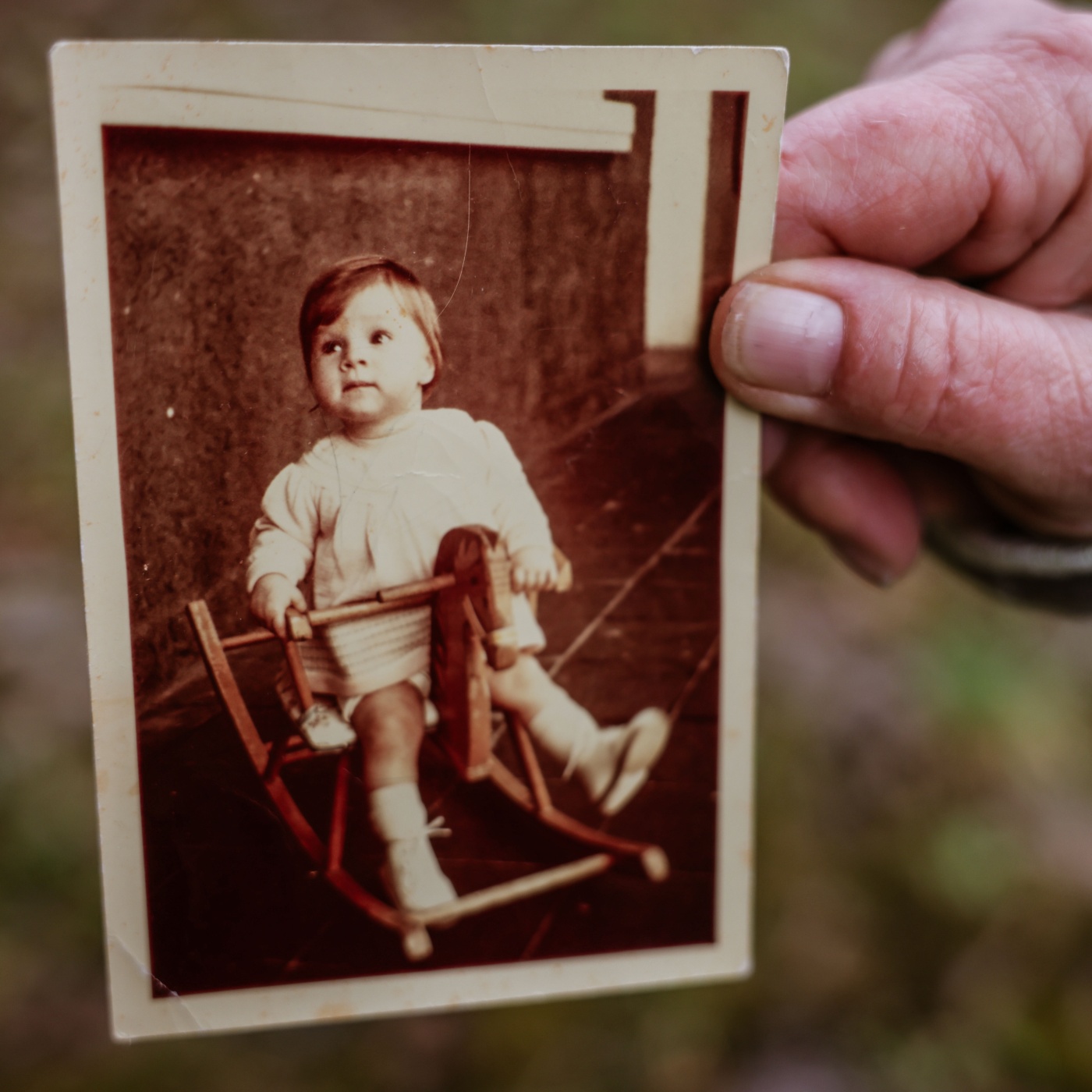 Eine Frau hält ein Bild von sich in der Hand, das sie als Verschickungskind zeigt.