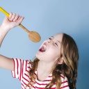 Mädchen singt lauthals mit Kochlöffel als Mikrofon
