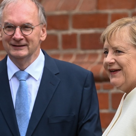 Reiner Haseloff (CDU), Ministerpräsident von Sachsen-Anhalt, begrüßt Bundeskanzlerin Angela Merkel (CDU) vor Beginn des ökumenischen Gottesdienstes an der Pauluskirche in Halle/Saale.