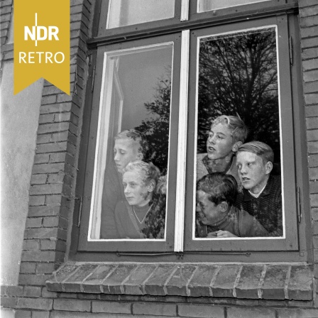 Neugierige Kinder schauen aus dem Fenster ihres Klassenzimmers, 1961