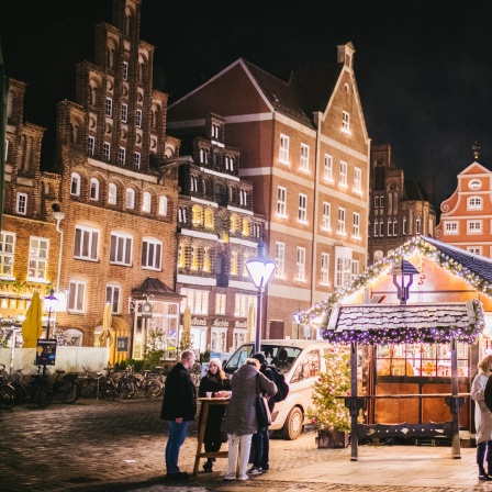 Menschen an einem weihnachtlichen Stand in der Altstadt von Lüneburg.