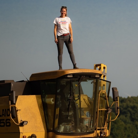 Hofinhaberin Susanne van Giffen steht auf einem Traktor.