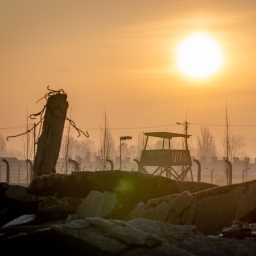 Die Sonne geht am frühen Morgen hinter der Ruine einer Gaskammer, den Stacheldrahtzäunen und Wachtürmen des früheren Vernichtungslagers Auschwitz-Birkenau auf.