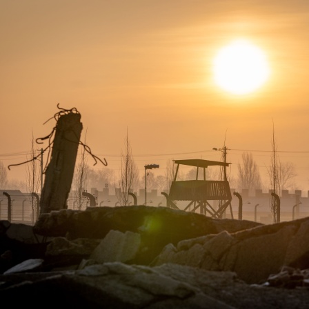 Die Sonne geht am frühen Morgen hinter der Ruine einer Gaskammer, den Stacheldrahtzäunen und Wachtürmen des früheren Vernichtungslagers Auschwitz-Birkenau auf.