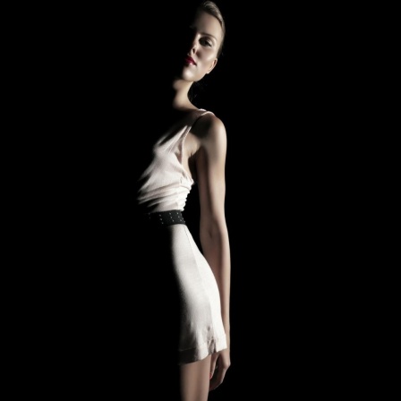 Eine junge Frau in weißem Kleid, umrahmt von Licht und Schatten, Fashion
