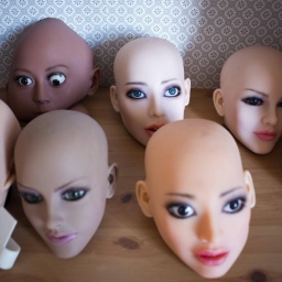 Weiblich aussehende Köpfe von Sexrobotern mit künstlicher Intelligenz stehen auf einer Holzfläche.