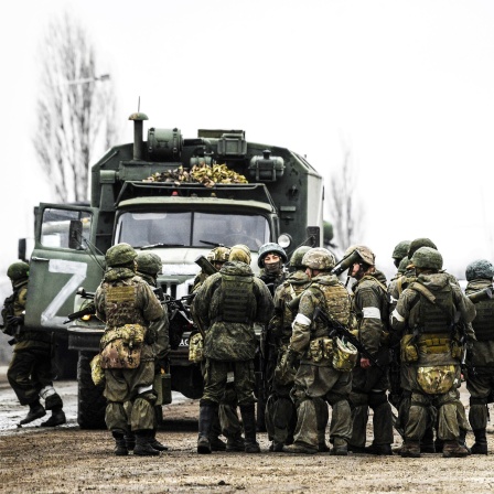 Das von der staatlichen russischen Nachrichtenagentur Sputnik veröffentlichte Bild zeigt russische Soldaten die in der Stadt im Norden der Krim neben einem Militärlastwagen stehen. Russland hat am Donnerstag einen umfassenden Angriff auf die Ukraine gestartet und Städte und Stützpunkte mit Luftangriffen oder Granaten beschossen.