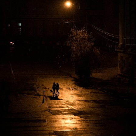Menschen laufen nachts während einer Stromsperre in Kiew über eine Straße.