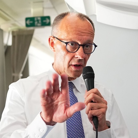 Bundeskanzler Friedrich Merz (CDU) spricht mit Journalisten im Flugzeug auf dem Weg vom BER nach Paris und Warschau.