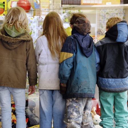 Vier Kinder sehen sich in einer Einkaufsstraße in Stade Spielsachen in einem Schaufenster an 