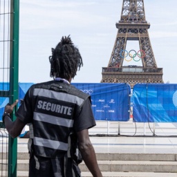 Sicherheitsmitarbeiter am Eiffelturm in Paris mit Olympischen Ringen