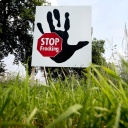 Plakat mit Aufschrift "Stop Fracking" steht auf einer Wiese.