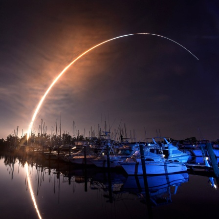 Eine Rakete zieht beim Start einen weiten, feurigen Bogen über den Nachthimmel von Florida.