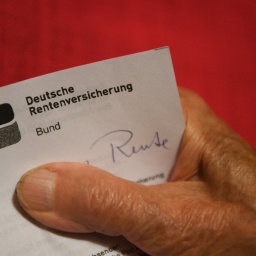 Eine Rentnerin hält ihren Rentenbescheid in der Hand.