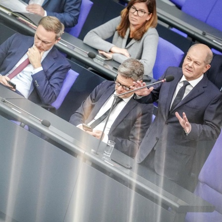 Bundeskanzler Olaf Scholz (SPD) spricht bei der Regierungsbefragung im Bundestag neben Finanzminister Christian Lindner (FDP) und Wirtschaftsminister Robert Habeck zu den Abgeordneten.