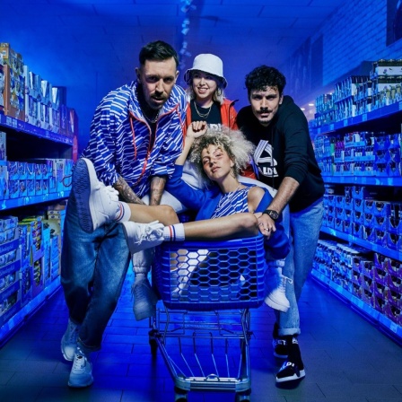 Zwei junge Männer und eine Frau stehen im Gang eines ALDI Supermarktes, in ihrer Mitte sitzt eine weitere Frau im Einkaufswagen.