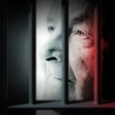 Ein Mann in Gefängnisszelle hinter Gittern.