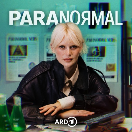 Paranormal Podcast mit Alli Neumann am Schreibtisch auf Akten gelehnt