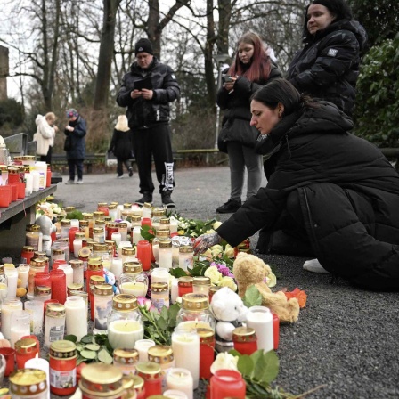 Menschen trauern an einer provisorischen Gedenkstätte mit Kerzen und Blumen für die Opfer des Messerangriffs in Aschaffenburg.