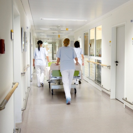 Krankenschwestern schieben ein Bett durch ein Krankenhaus.