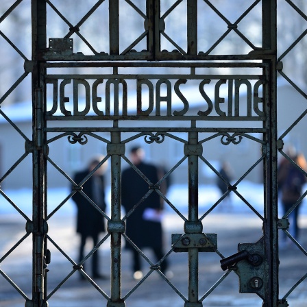 Besucher stehen am Lagertor der KZ-Gedenkstätte Buchenwald bei Weimar mit der Inschrift Jedem das Seine